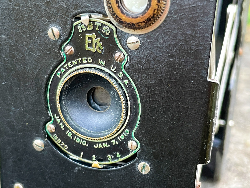 Messingschild mit Verschlusszeiten und Blendeneinstellungen auf der Frontseite der Vest Pocket Autographic Kodak Kamera
