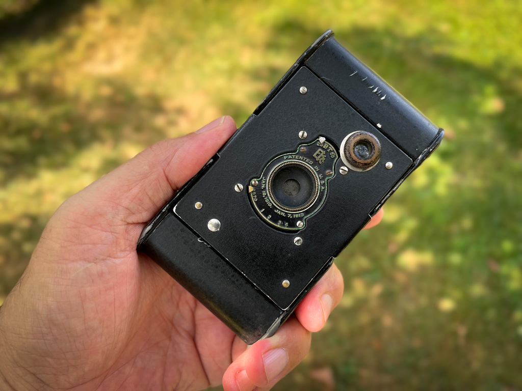 Vest Pocket Autographic Kodak Kamera wird in einer Hand gehalten. Damit ist ein Grössenvergelich möglich, der zeigt, wie klein die Kamera eigentlich ist.