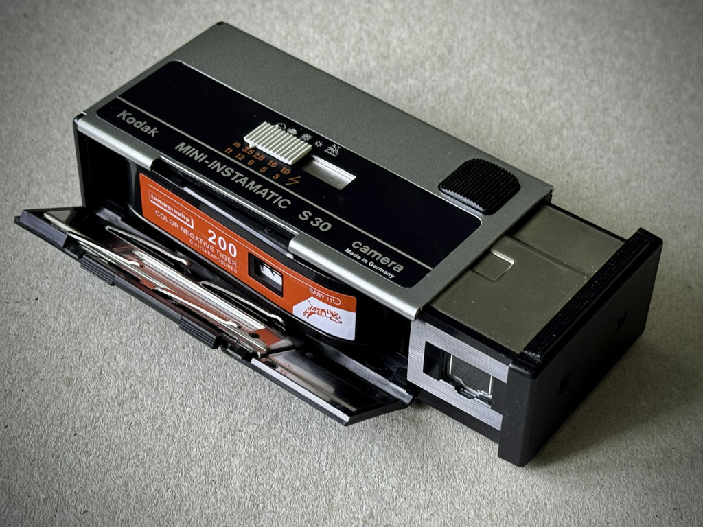 Kodak Mini Instamatic S30 mit geöffneter Rückwand und eingelegter Filmkassette.
