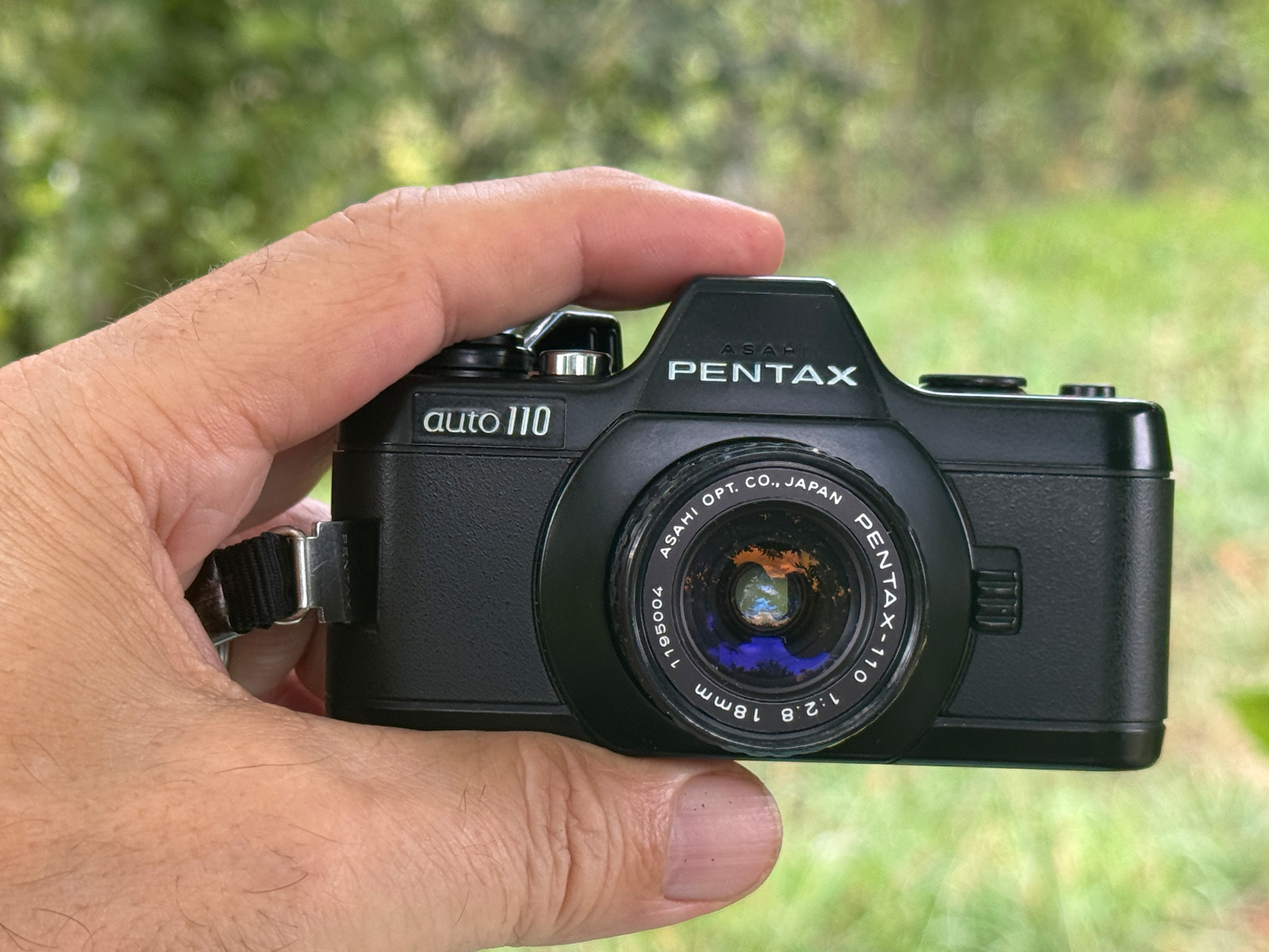 Die PENTAX auto 110 zwischen Daumen und Zeigefinter in der Hand gehalten.